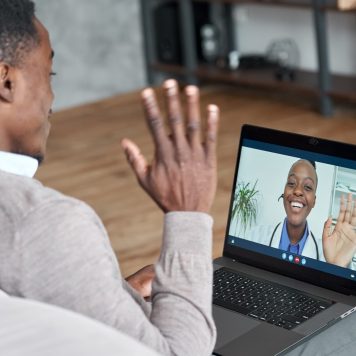 Male black patient talking on conference video call to female african doctor. Virtual therapist consulting young man during online appointment on laptop at home. Telemedicine chat, telehealth meeting